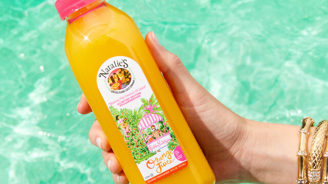 Hand holding orange juice bottle